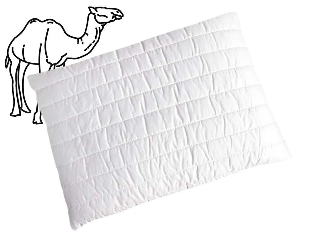 Ein weißes, gestepptes Kissen mit horizontalen Stepplinien auf einfarbigem Hintergrund. In der oberen linken Ecke befindet sich eine einfache schwarze Umrisszeichnung eines Kamels.