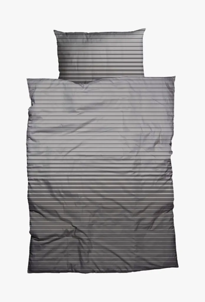Die Bettwäsche Nobilium Weilo, bestehend aus einem Kissen und einer Decke mit grauen und schwarzen Querstreifen, ist flach auf weißem Grund angeordnet.
