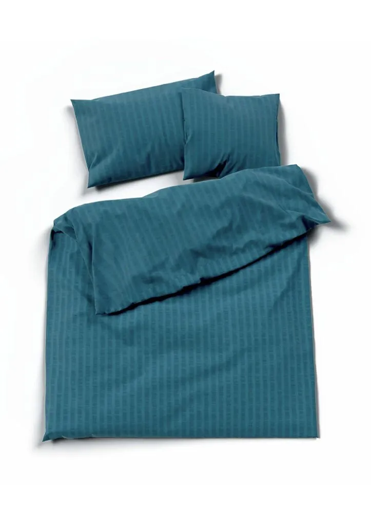 Ein tealblaues Bettset mit dezentem Streifenmuster, bestehend aus einem Bettbezug und zwei Kissenbezügen auf weißem Grund - eine ideale Ergänzung zu den rosa Bettwäsche Satin Seersucker Modellen.