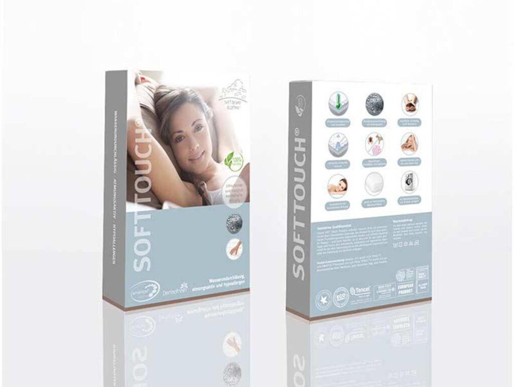 Zwei Fixleintuch Softtouch Antibac wasserdicht-Schachteln stehen aufrecht - auf der einen ist eine lächelnde Frau zu sehen, die sich entspannt, während auf der anderen Produktmerkmale und Symbole auf einem klaren weißen Hintergrund zu sehen sind.