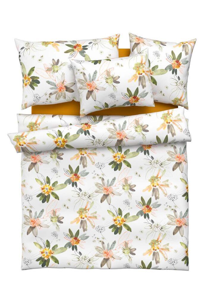 Ein sauber arrangiertes Bettwäscheset mit einem Blumenmuster in Grün-, Gelb-, Orange- und Beigetönen auf weißem Grund, bestehend aus einem Bettbezug, zwei Kissen und einem kleineren Kissen.