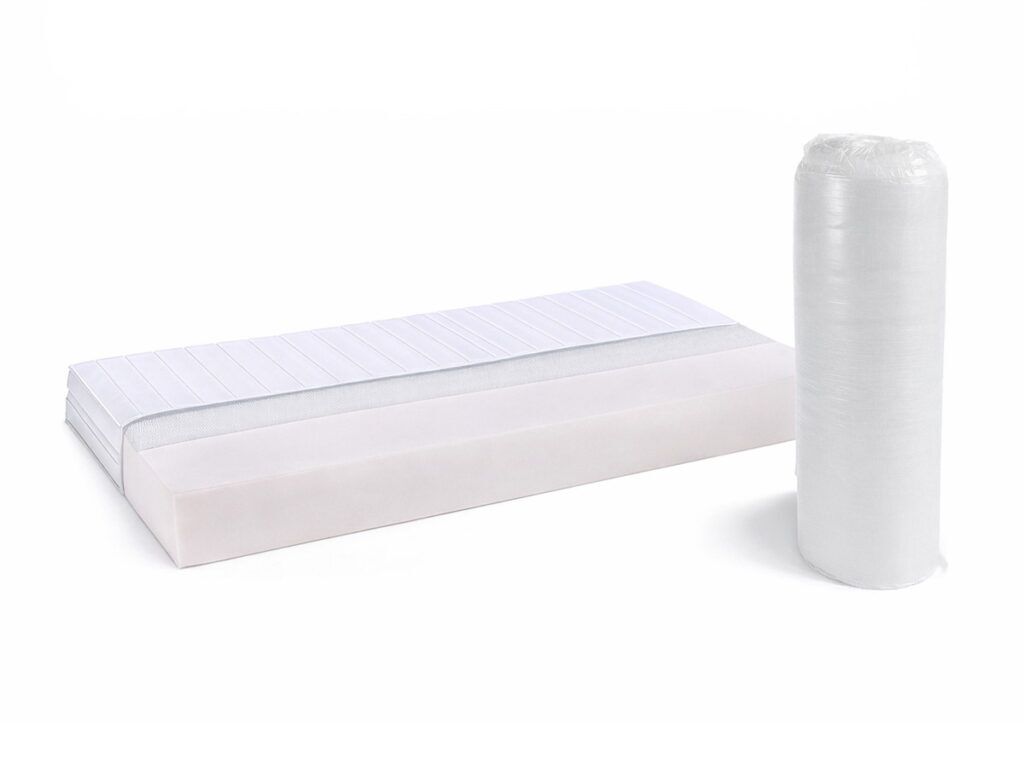 Eine rechteckige Matratze wird neben ihrer aufgerollten, vakuumversiegelten Verpackung auf weißem Hintergrund gezeigt. Die Matratze hat einen mehrschichtigen Aufbau mit verschiedenen Weiß- und Grautönen.