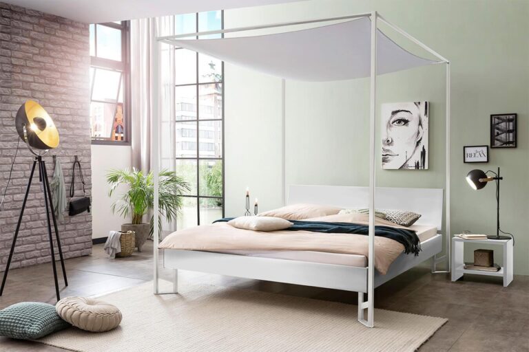 Modernes Schlafzimmer mit weißem Himmelbett, beiger Bettwäsche und einer dunkelgrünen Decke. Große Fenster lassen viel natürliches Licht herein. Zur Ausstattung gehören eine Stehlampe, Zimmerpflanzen, ein Schwarz-Weiß-Porträt und minimalistische Möbel.