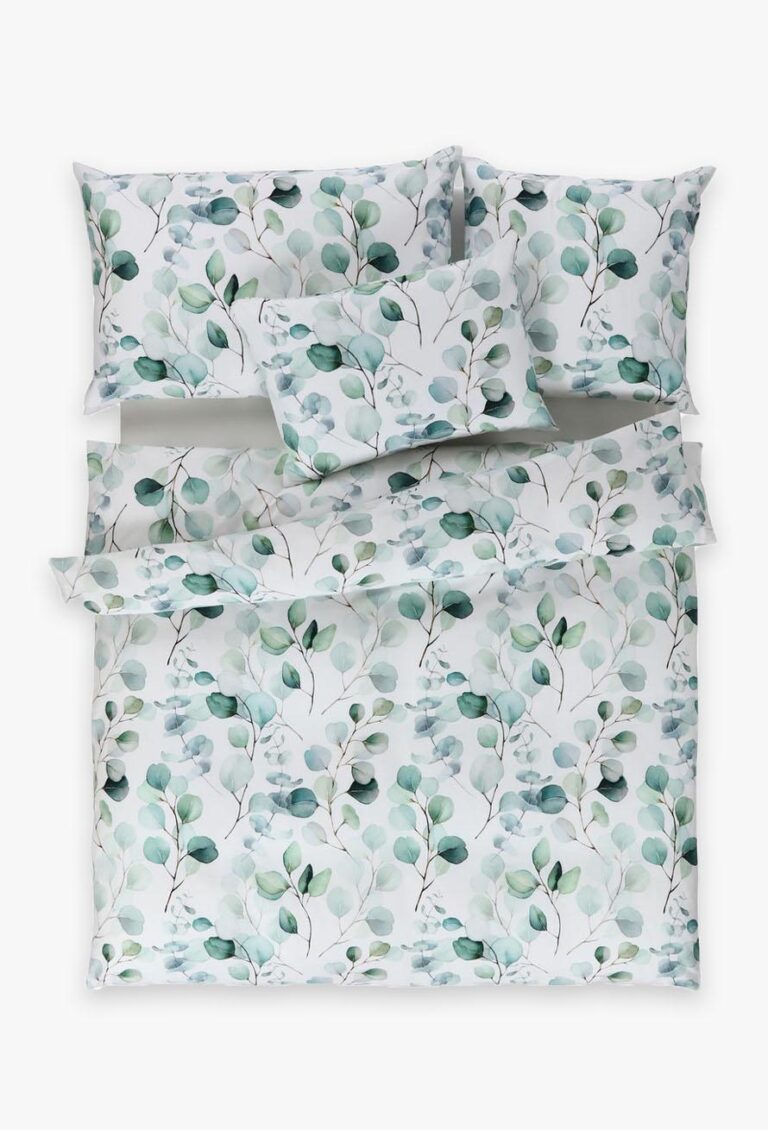 Ein ordentlich gemachtes Bett mit weißen Laken, Kissenbezügen und einem Bettbezug mit einem hellgrünen und blauen Eukalyptusblattmuster auf weißem Hintergrund. Auf dem Bett sind vier Kissen angeordnet.