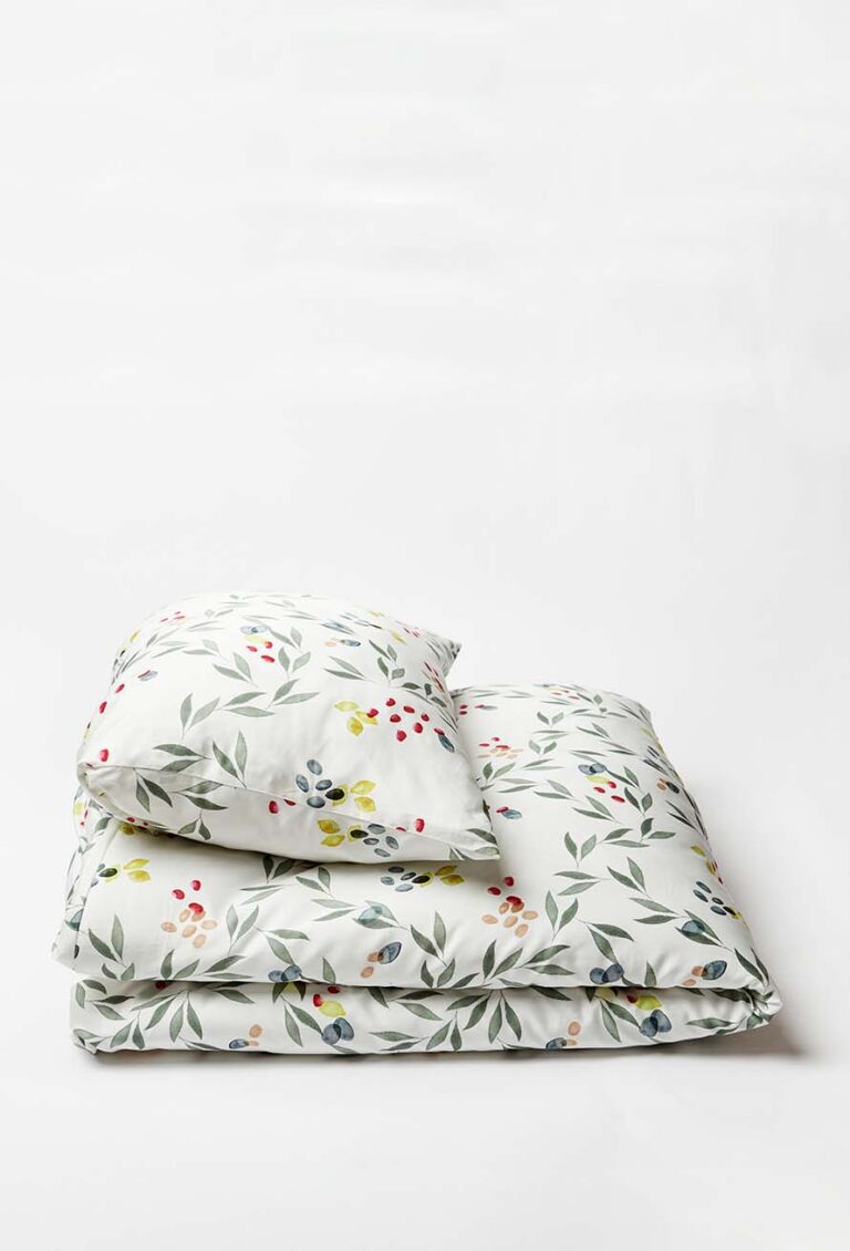 Die Bettwäsche Journey Living Amiata besteht aus einem weißen Kissen und einer gefalteten Bettdecke mit einem dezenten Blatt- und Beerendruck in Grün, Gelb, Rot und Blau auf einem schlichten weißen Hintergrund.