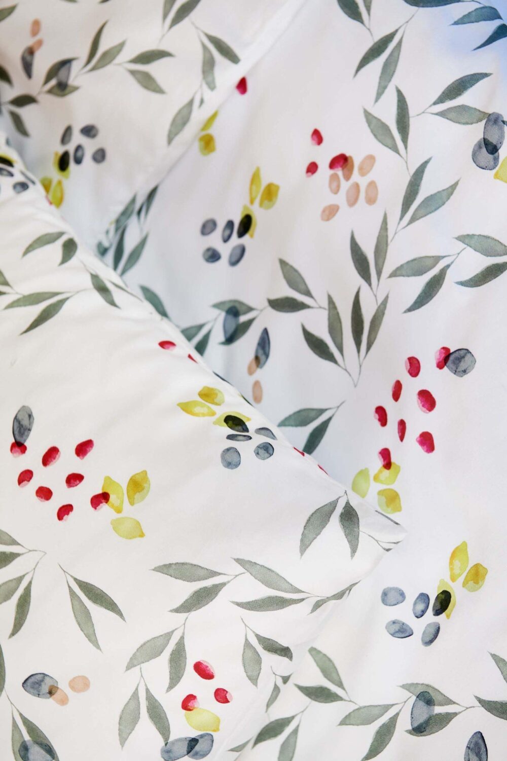 Nahaufnahme der Bettwäsche Journey Living Amiata mit einem Muster im Aquarellstil mit grünen Blättern und leuchtenden Beerenbüscheln. Das weiche, organische Design verleiht einen frischen, botanischen Look.