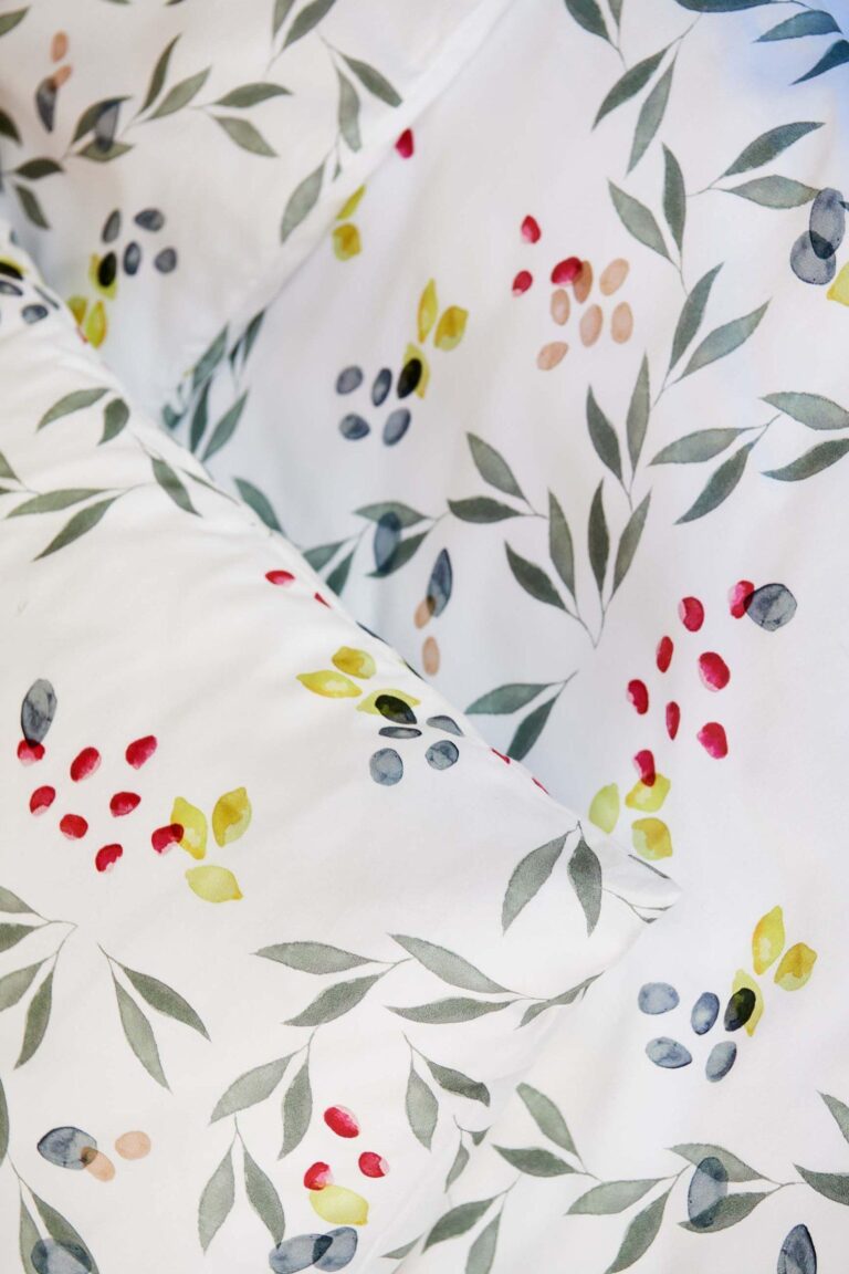 Nahaufnahme der Bettwäsche Journey Living Amiata mit einem Muster im Aquarellstil mit grünen Blättern und leuchtenden Beerenbüscheln. Das weiche, organische Design verleiht einen frischen, botanischen Look.