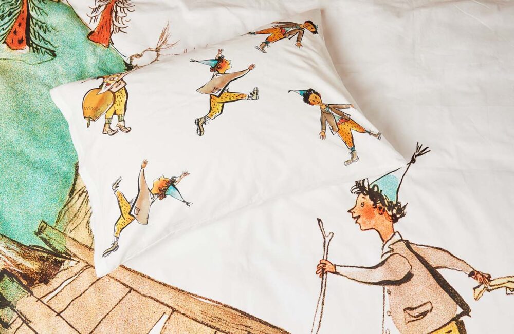 Der Bettwäsche Schellenursli Aufzug zeigt fröhliche Illustrationen von Kindern mit blauen Hüten und gelben Hosen inmitten von Bäumen und bringt eine fröhliche Note in jedes Kinderzimmer.