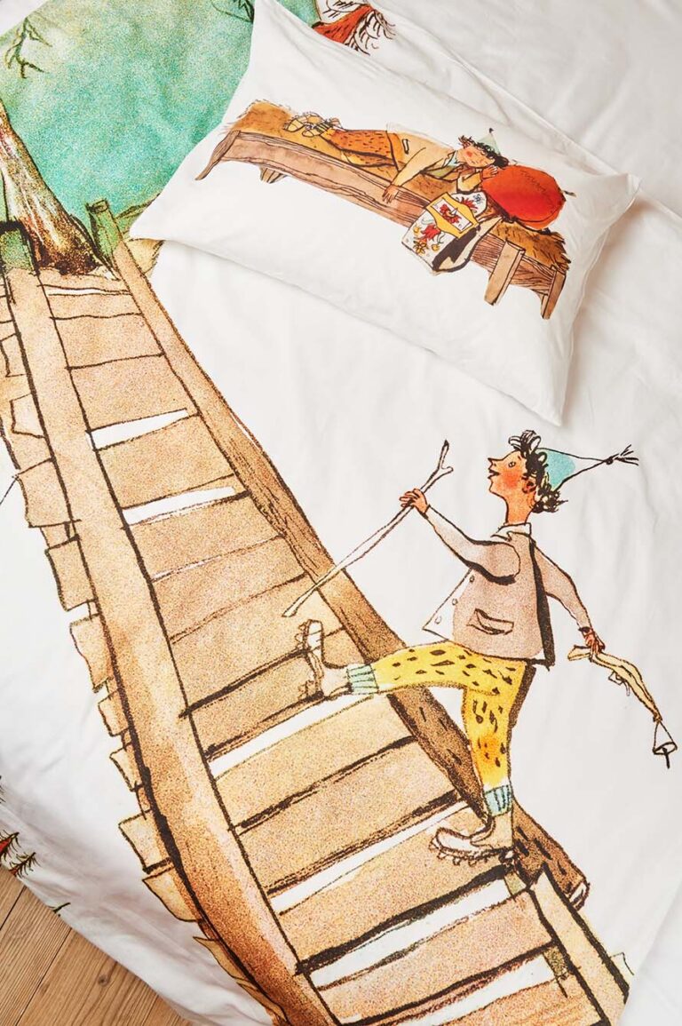 Der Bettwäsche Schellenursli Aufzug zeigt ein verspieltes Design mit einem Jungen mit blauem Partyhut und gelber Hose, der eine Holztreppe hinaufläuft, sowie ein Kissen, das jemanden zeigt, der auf einer Bank liegt - perfekt, um jedem Kinderzimmer Charme zu verleihen.