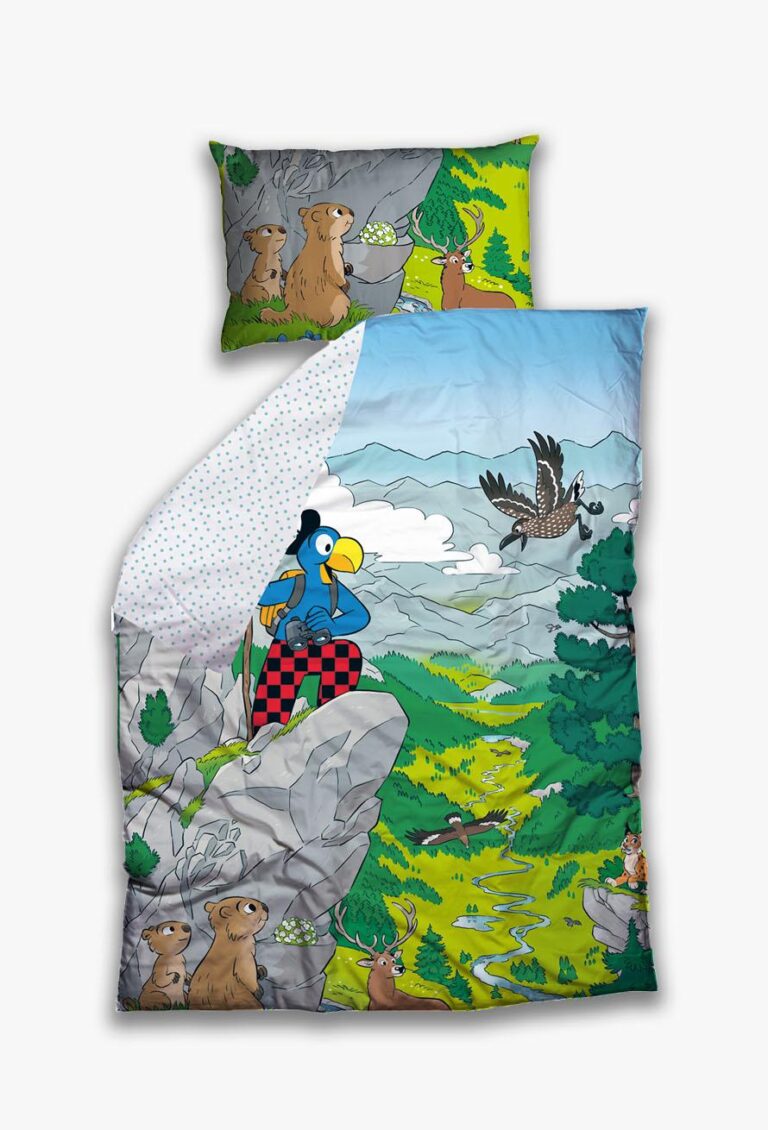Das Bettwäsche Globi Nationalpark Set zeigt eine farbenfrohe Szene mit Globi, dem blauen Vogel in karierter Hose, der auf einer felsigen Klippe steht, mit Murmeltieren, Rehen, einem Adler und üppiger grüner Nationalpark-Landschaft. Der Kissenbezug passt zum farbenfrohen Design.