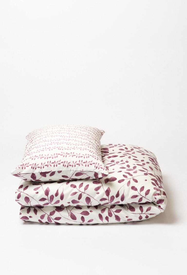 Das Bettwäsche-Set Journey Living Pérouges zeigt rosa und violette Blattmuster auf weißem Stoff - das Kissen mit einem dichteren Muster und die Bettdecke mit einer großzügigeren Anordnung.