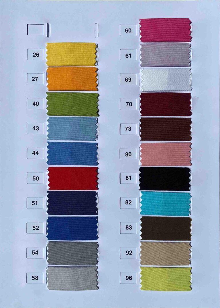 Eine Farbkarte zeigt 20 Lotus Fixleintuch Souplesse Jersey Muster in einem vertikalen Raster, jedes nummeriert und mit Farbtönen von Gelb und Orange bis Blau, Rot, Braun, Schwarz, Grau und verschiedenen Pastelltönen.