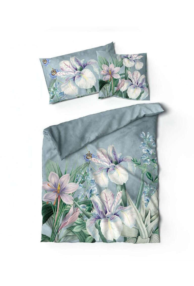 Die Bettwäsche Iris Lotus Création hat einen blau-grauen Hintergrund mit großen weißen, lila und rosa Blüten, grünen Blättern und kleinen blauen Akzenten auf dem Bettbezug und den Kissenbezügen.