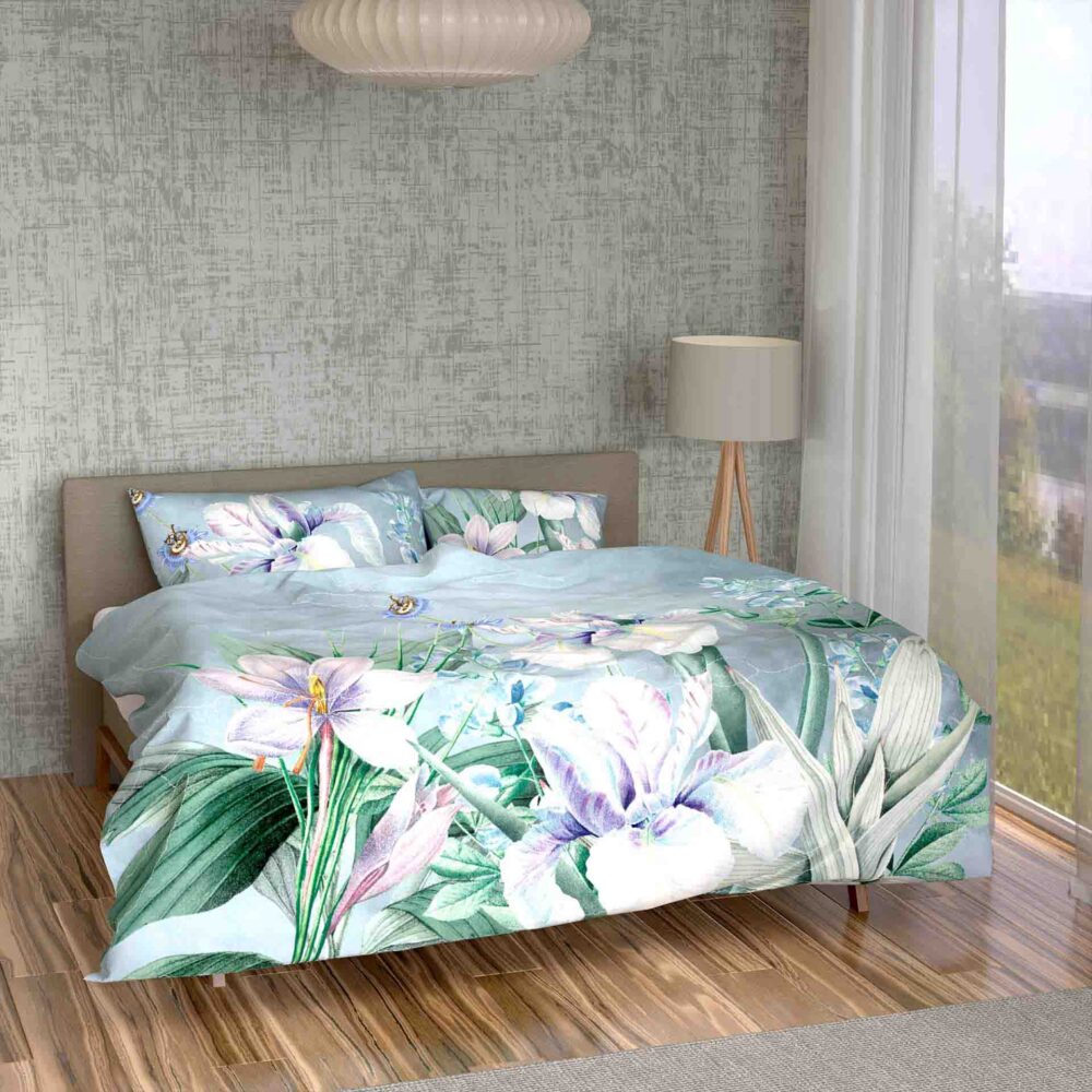 Ein modernes Schlafzimmer mit hellem Holzfußboden präsentiert die Bettwäsche Iris Lotus Création mit einer geblümten Bettdecke und pastellfarbenen Kissen, ergänzt durch eine Stehlampe und ein großes Fenster mit transparenten Vorhängen, die natürliches Licht hereinlassen.