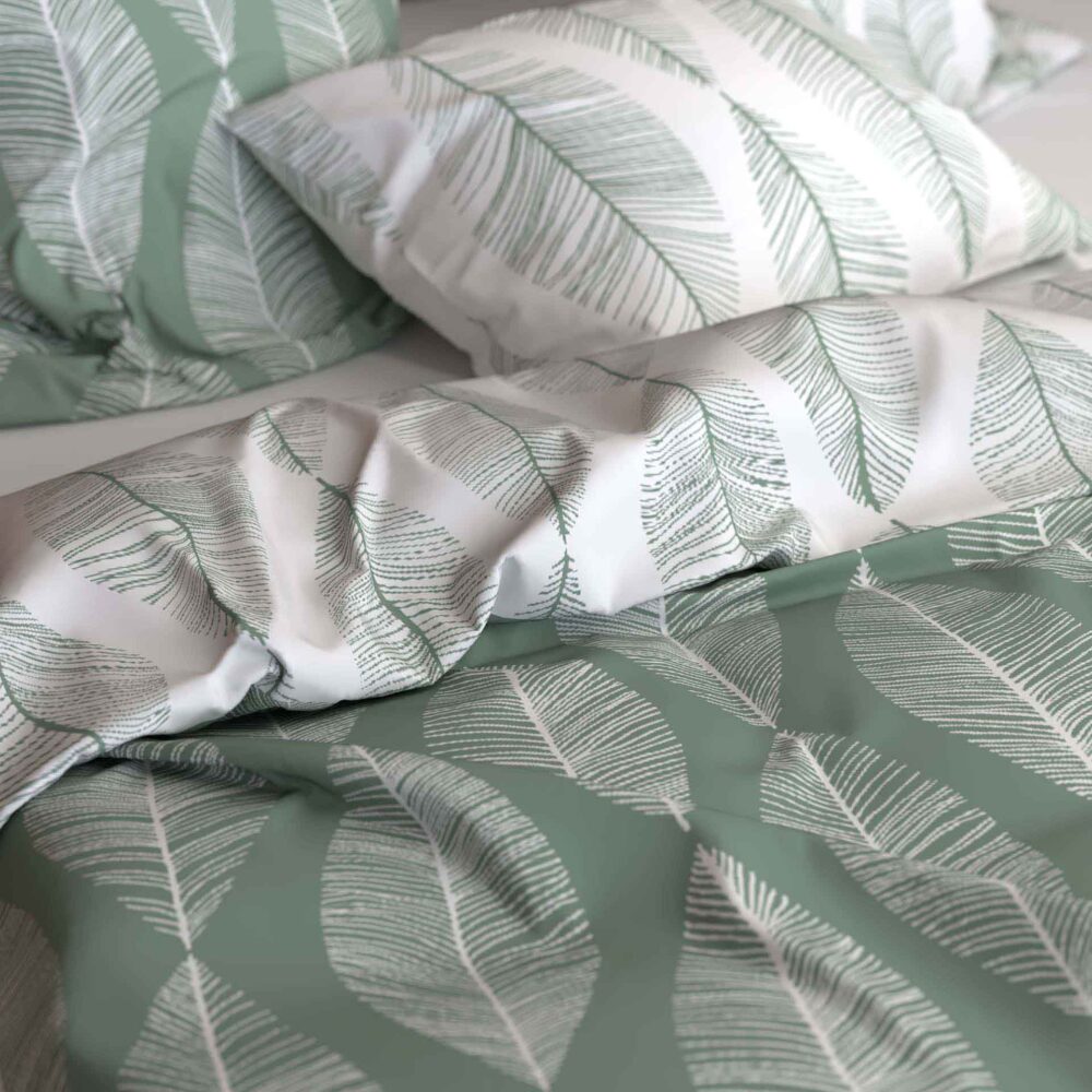 Nahaufnahme eines Bettes mit Kissen und einer Bettdecke aus Bettwäsche Ruben Lotus Création, mit großen grünen und weißen stilisierten Blättern für einen modernen, von der Natur inspirierten Look.