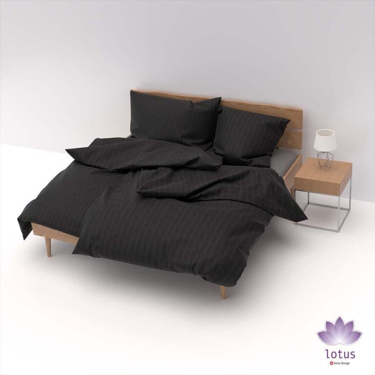 Ein ordentlich gemachtes Holzbett mit Bettwäsche Satin Seersucker Schwarz und Kissen steht neben einem hölzernen Nachttisch mit einer Lampe. Das Zimmer hat weiße Wände und einen weißen Boden, mit einem lila Lotus-Logo in der unteren rechten Ecke.