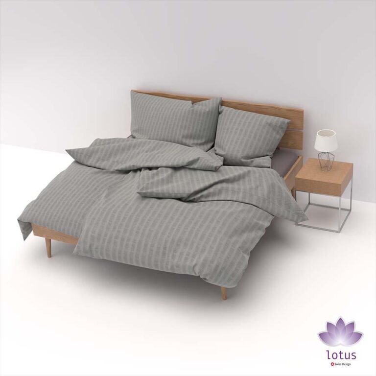 Ein ordentlich gemachtes Bett mit einem hölzernen Kopfteil zeigt grau gestreifte Bettwäsche Satin Seersucker titan, neben einem hölzernen Nachttisch mit einer modernen Lampe. Ein lila Lotus-Logo erscheint in der unteren rechten Ecke.