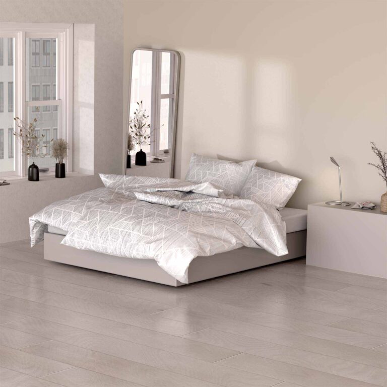 Ein modernes Schlafzimmer mit einem sauber gemachten Bett mit Bettwäsche Nalani Lotus Création, einem geometrisch gemusterten weißen Bettwäscheset, einem Bodenspiegel, einem Fenster mit Stadtblick, Vasen, einem Nachttisch, einer Schreibtischlampe und einem hellen Holzfußboden.