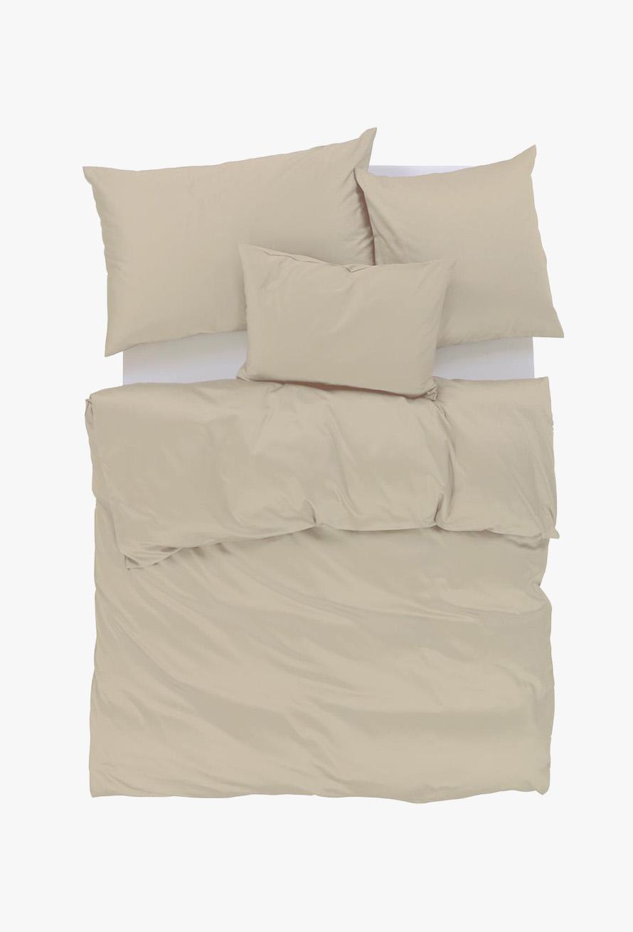 Draufsicht auf ein ordentlich gemachtes Bett mit beiger Bettwäsche, einschließlich zweier Kissen, eines langen rechteckigen Kissens und einer Bettdecke, alles vor einem weißen Hintergrund.