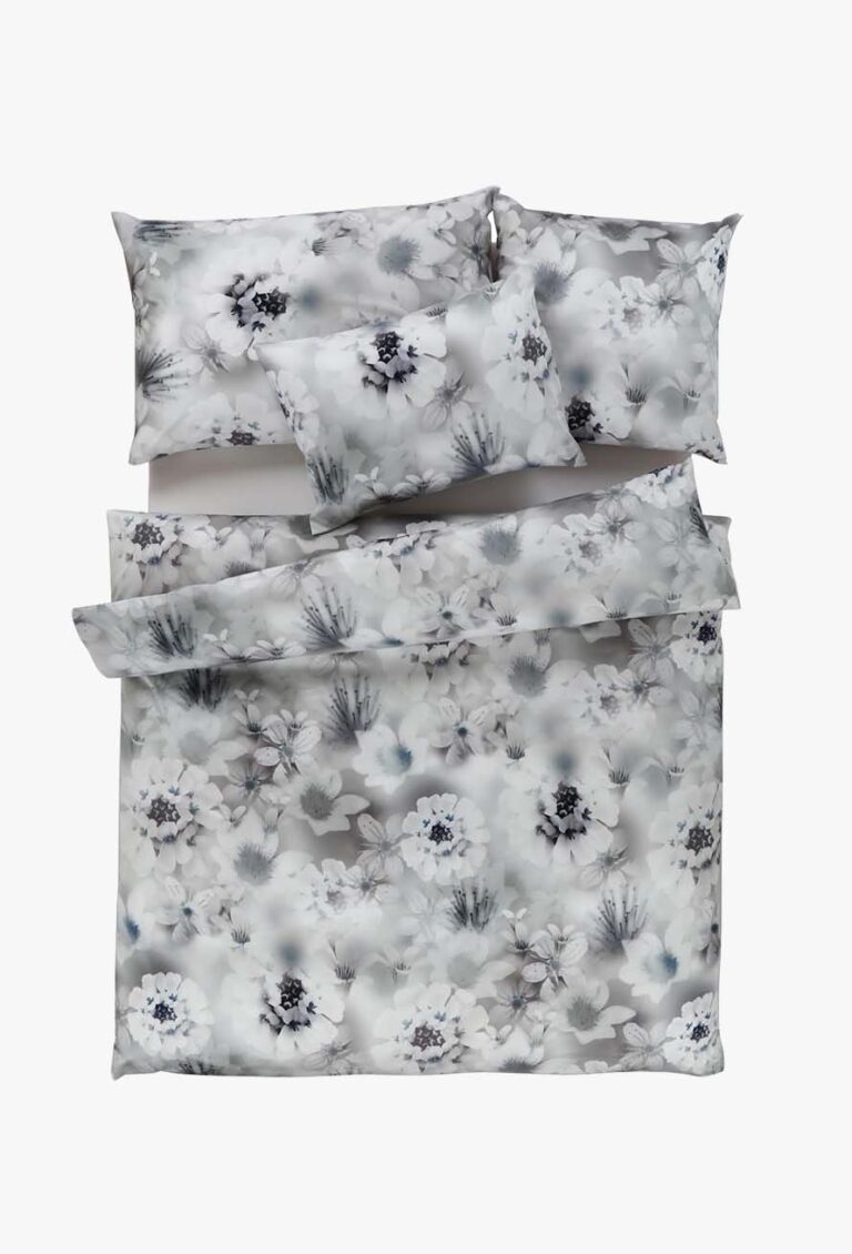 Ein ordentlich gemachtes Bett mit der Bettwäsche Tamara-R Selection Irina, bestehend aus einem Bettbezug, zwei Kissen und einem Kissen in einem grau-weißen Blumenmuster mit schwarzen und blauen Akzenten auf weißem Hintergrund.