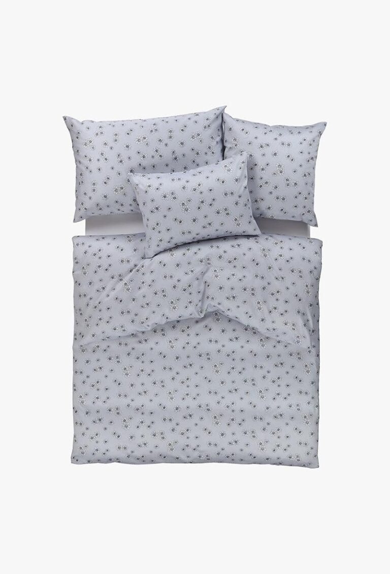 Ein ordentlich gemachtes Bett mit Bettwäsche Edelweiss silber: eine hellgraue Bettdecke und vier passende Kissen, jedes mit einem dezenten Blumenmuster auf einem unifarbenen Hintergrund verziert, von oben auf einem weißen Hintergrund betrachtet.