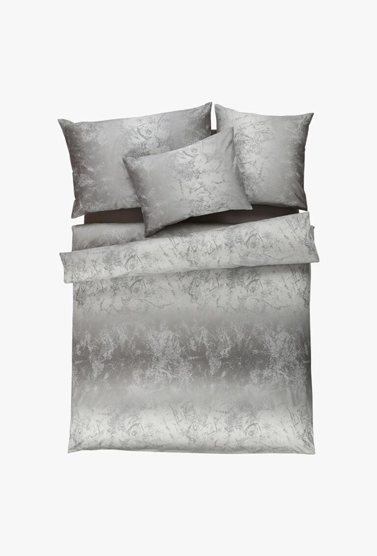 Ein ordentlich gemachtes Bett präsentiert die Bettwäsche Tamara-R Selection Royal silber: silberne Bettwäsche mit einem strukturierten, eleganten Muster und passenden Kissenbezügen auf weißem Grund.