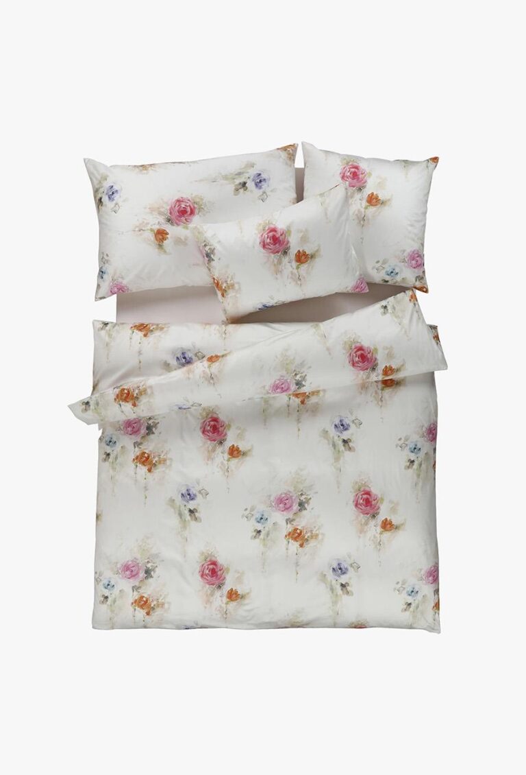 Ein ordentlich gemachtes Bett zeigt die Bettwäsche Tamara-R Selection Sabina mit einem floralen Aquarellmuster in Rosa, Orange und Lila. Zum Set gehören eine Bettdecke und vier Kissen, alle mit demselben zarten Muster.