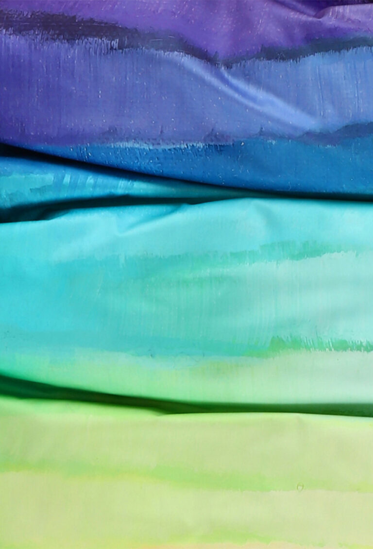 Eine Nahaufnahme von vier horizontalen Stofflagen von Bettwäsche Tamara-R Selection Regenbogen: oben lila, darunter blau, türkis und hellgrün - jede Lage zeigt weiche Farbverläufe und eine subtile Textur.