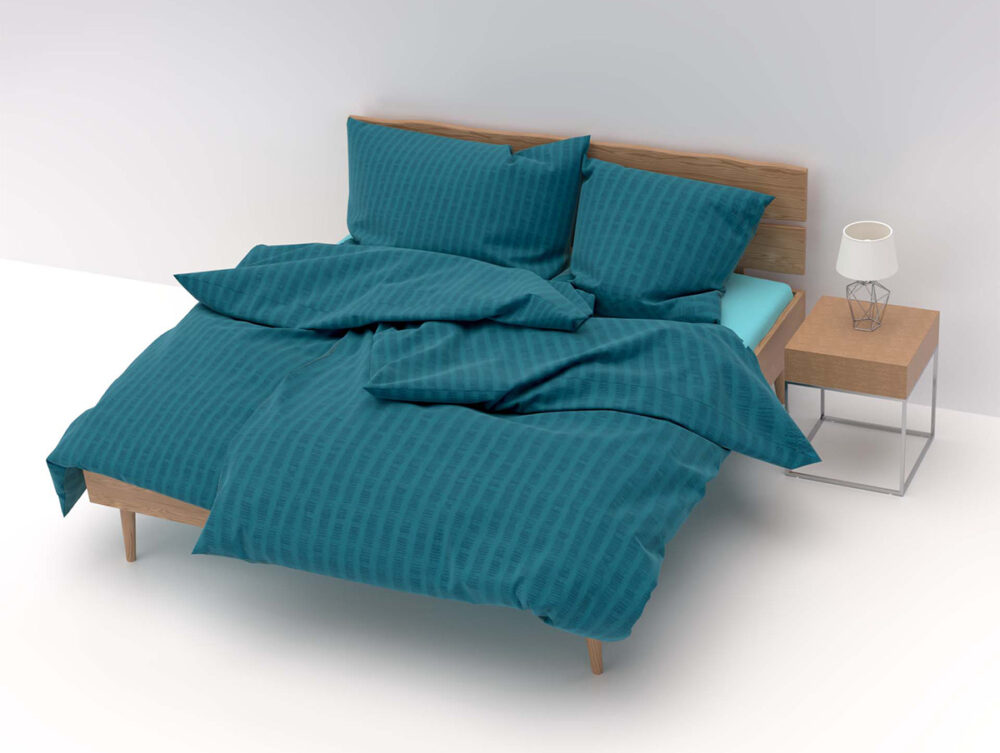 Ein ordentlich gemachtes Bett mit Bettwäsche Satin Seersucker rosa und passenden Kissen steht neben einem hölzernen Nachttisch mit einer kleinen weißen Lampe, alles vor einem schlichten weißen Hintergrund.