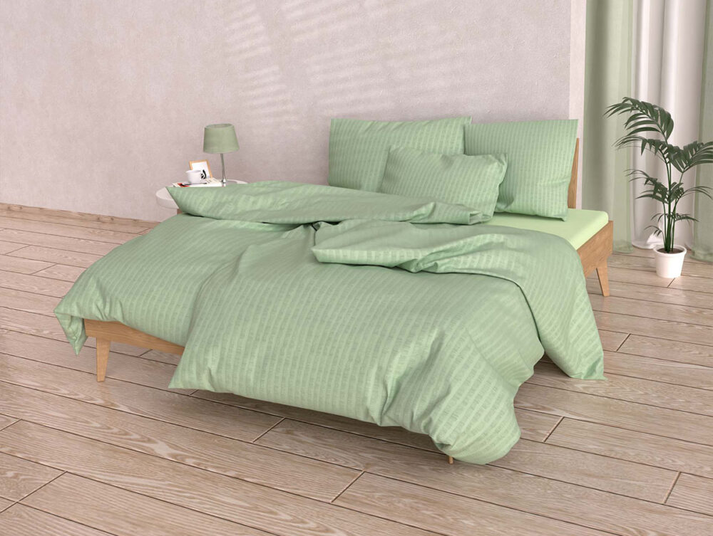 Ein ordentlich gemachtes Bett mit Bettwäsche Satin Seersucker rosa und mehreren Kissen steht in einem modernen Zimmer mit hellem Holzboden, einem Nachttisch mit Lampe und Bilderrahmen, einer Topfpflanze und hellen Wänden.