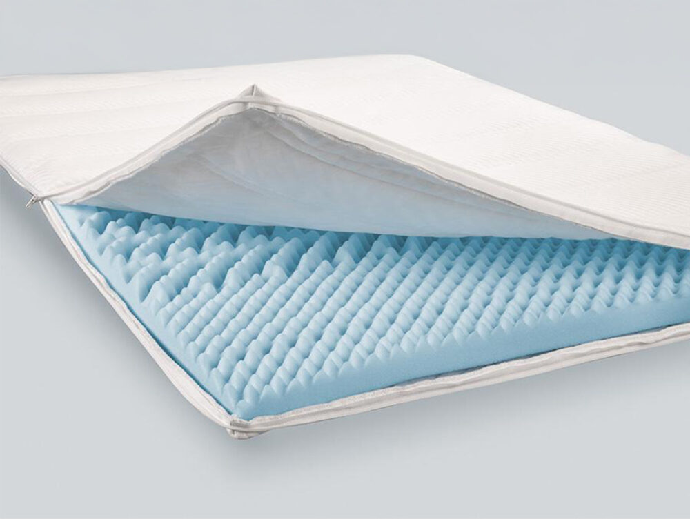 Eine Matratzenauflage mit weißem Bezug, die teilweise geöffnet werden kann, um blauen Eierkartonschaum für Komfort und Unterstützung zu zeigen - ideal für das Hasena Boxspringbett Classic "James Fiona".