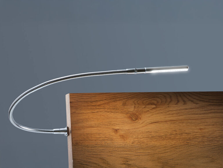 Eine moderne, biegsame Schwanenhals-LED-Lampe ist an der Kante einer hölzernen Oberfläche befestigt und beleuchtet das Holz vor einem schlichten grauen Hintergrund.