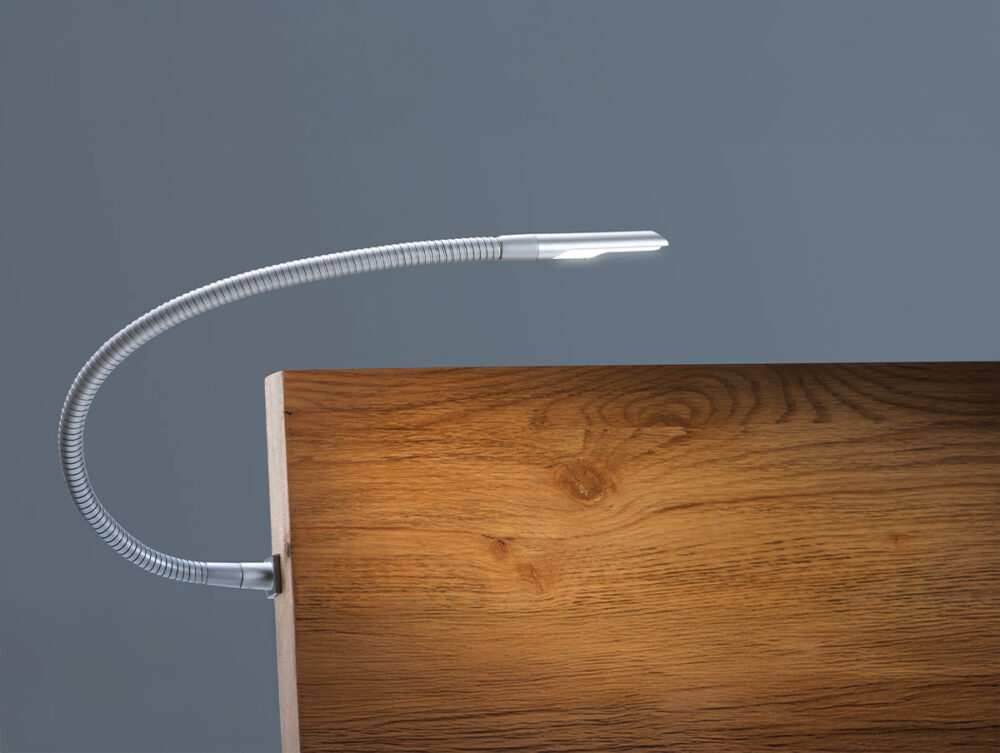 Eine biegsame, silberne Schwanenhals-LED-Lampe wird an die Kante einer Holzoberfläche geklemmt und beleuchtet den Bereich mit einem weichen Licht vor einem schlichten grauen Hintergrund.