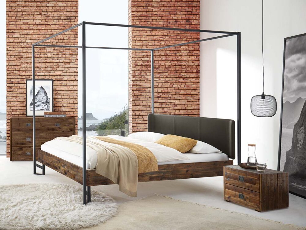 Modernes Schlafzimmer mit Himmelbett, Backsteinwänden, flauschigem weißen Teppich, rustikalen Holzmöbeln, großem Fenster mit Blick auf Wasser und Berge und einem schwarz-weiß gerahmten Landschaftsfoto auf dem Boden.