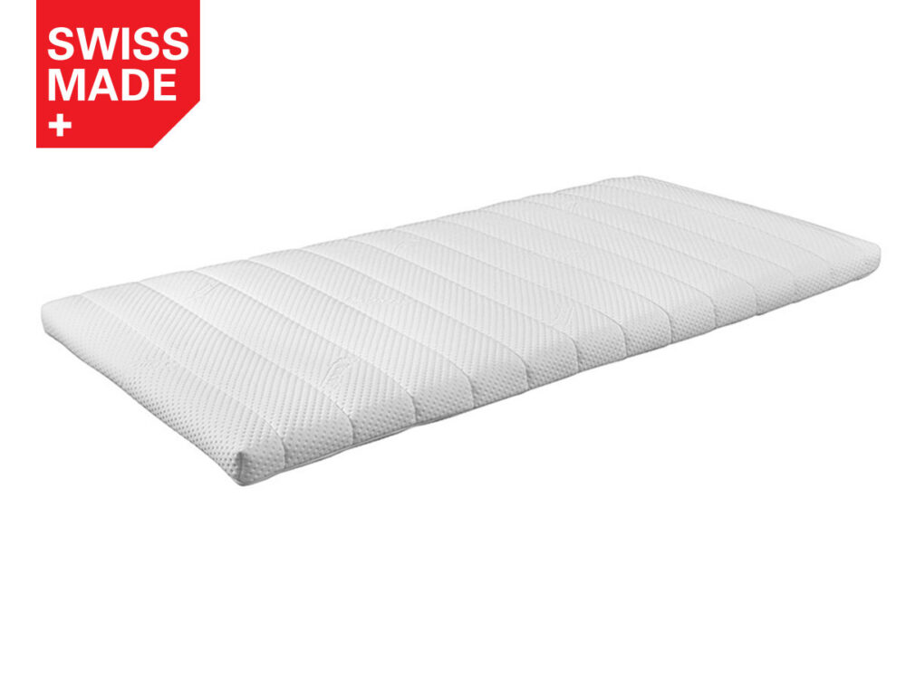 Eine weiße, rechteckige Matratzenauflage mit einer strukturierten Oberfläche ist auf weißem Hintergrund abgebildet. In der oberen linken Ecke befindet sich ein rotes Etikett mit der Aufschrift SWISS MADE und einem weißen Kreuzsymbol.