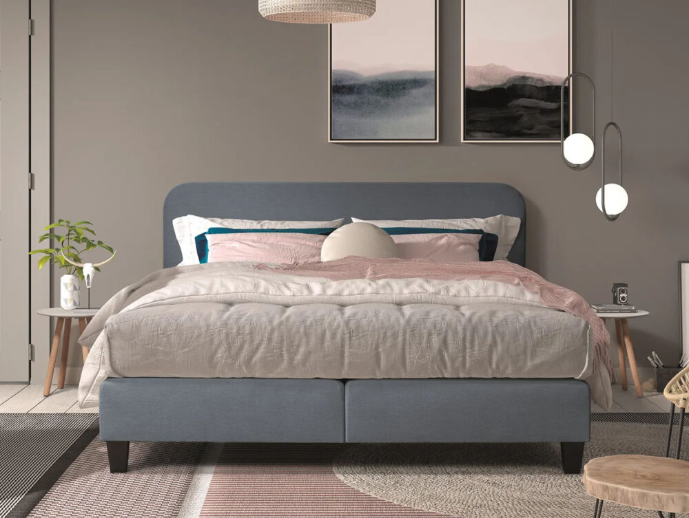 Ein modernes Schlafzimmer mit einem ordentlich gemachten Bett mit hellgrauer und errötender Bettwäsche, flankiert von zwei minimalistischen Nachttischen mit Pflanzen und Dekor. Abstrakte Kunst hängt an der grauen Wand über dem Bett.