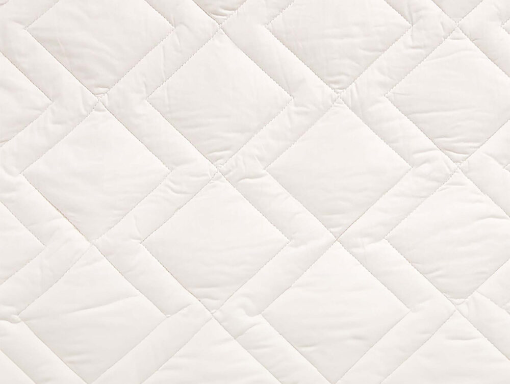 Nahaufnahme eines gesteppten Stoffes mit Rautenmuster, der weiße Nähte und eine weiche, gepolsterte Textur aufweist. Die Oberfläche erscheint glatt und sauber, mit leichten Falten und Nähten zwischen den Rautenformen.