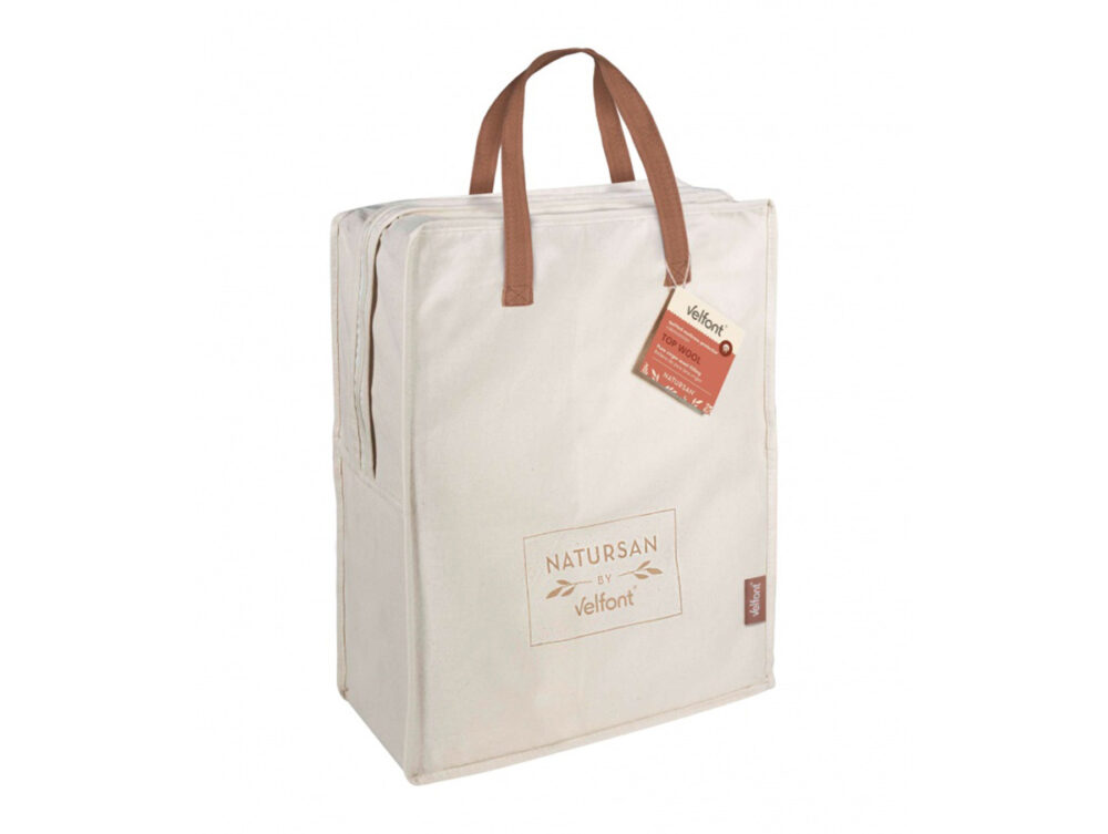 Ein beiger rechteckiger Stoffbeutel mit braunen Henkeln, Reißverschluss und NATURSAN by Velfont-Logo auf der Vorderseite enthält eine Velfont Top Wool Matratzenauflage. Das Produktetikett ist an einem Henkel befestigt.