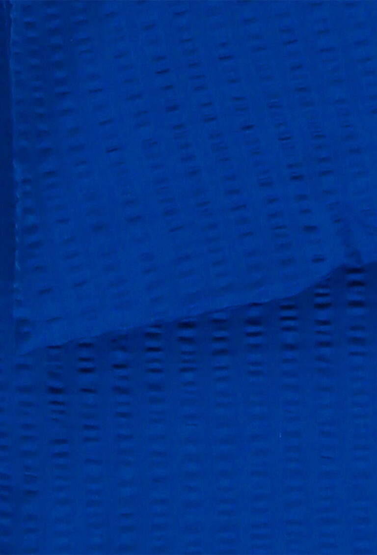 Nahaufnahme eines strukturierten blauen Stoffes mit einem dezenten Muster und einer gefalteten Kante, die kleine horizontale und vertikale Linien im gesamten Material zeigt.