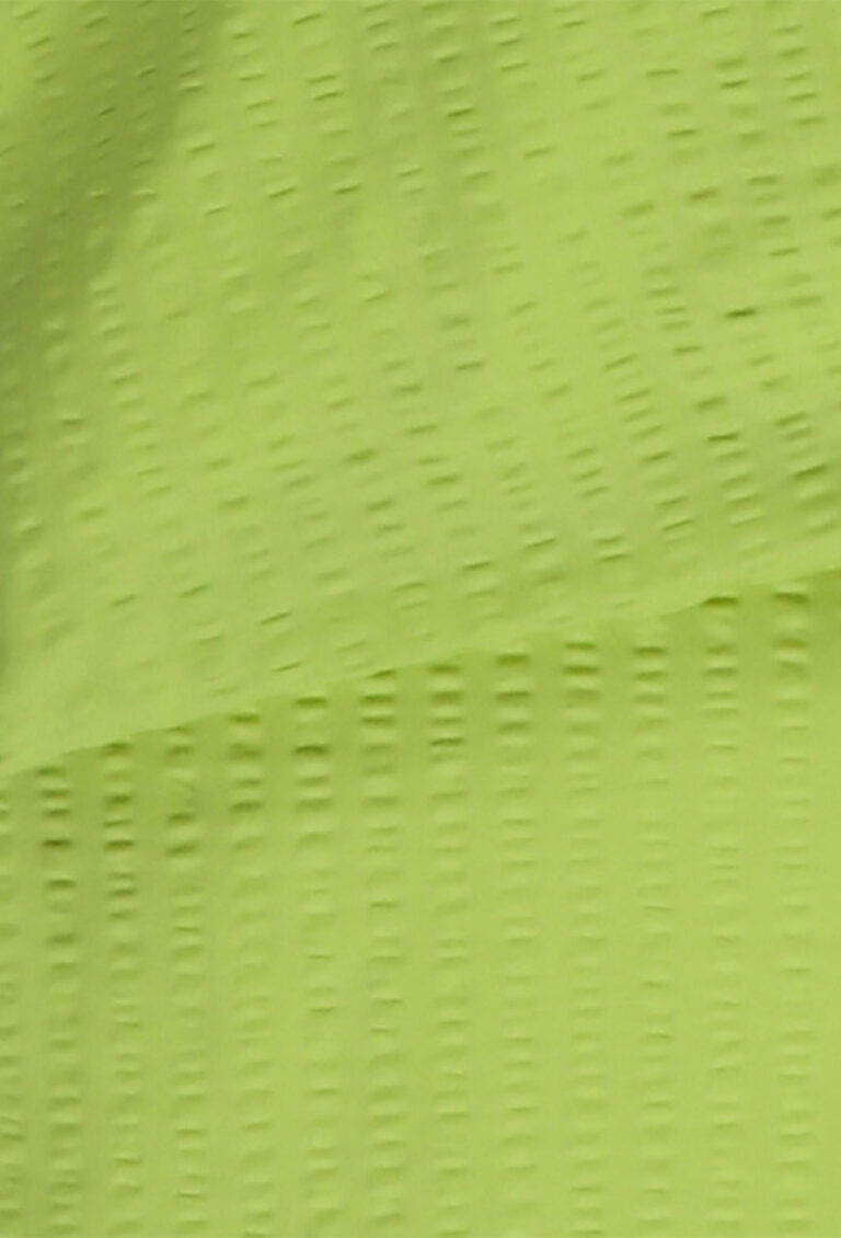 Nahaufnahme eines strukturierten, hellgrünen Stoffes mit einem Muster aus kleinen, in Reihen angeordneten rechteckigen Perforationen.