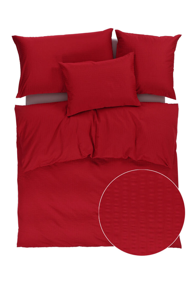 Ein rotes Bettwäscheset mit einem Bettbezug und drei Kissen, die alle mit einem dezenten Strukturmuster versehen sind. Eine kreisförmige Nahaufnahme hebt die gitterartige Textur des Stoffes hervor. Die Bettwäsche ist ordentlich auf einem weißen Hintergrund angeordnet.