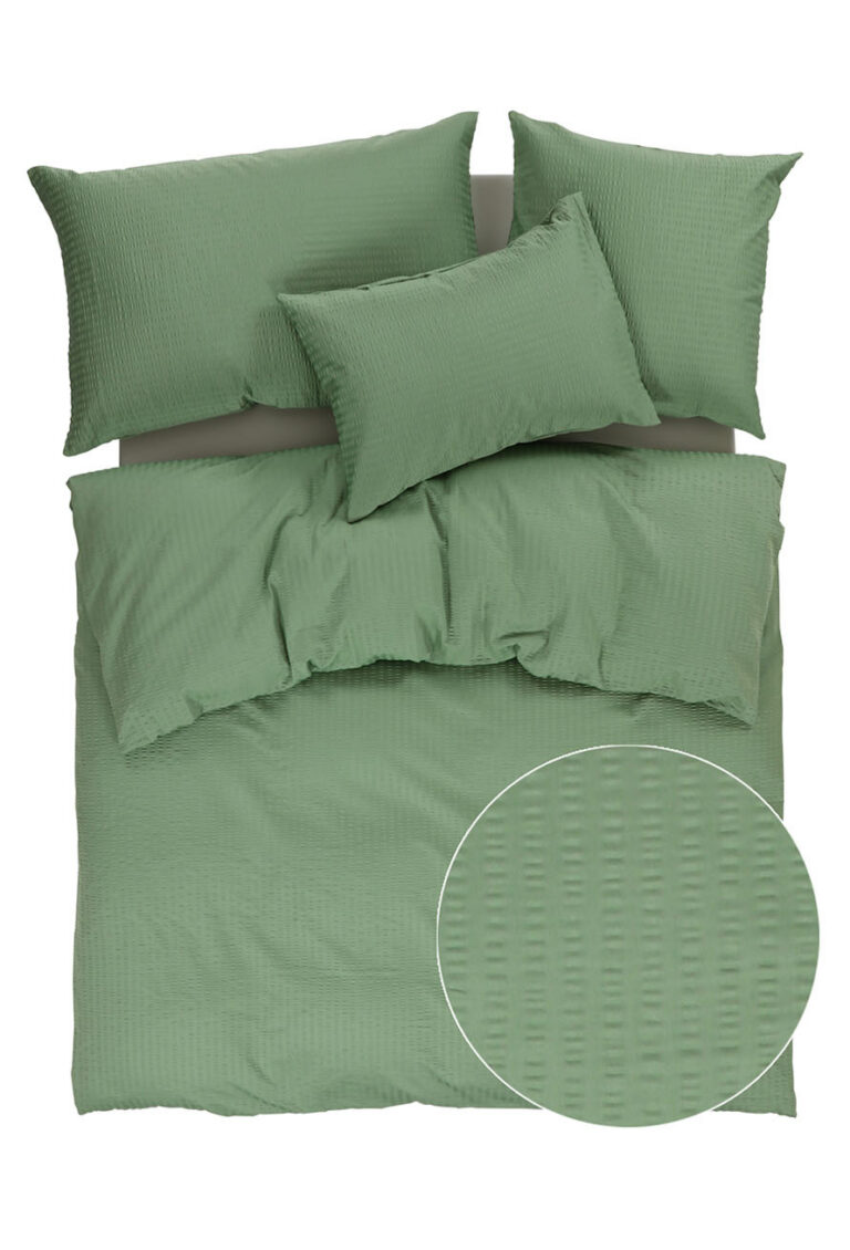 Ein Bett mit grünen Laken und Kissen.