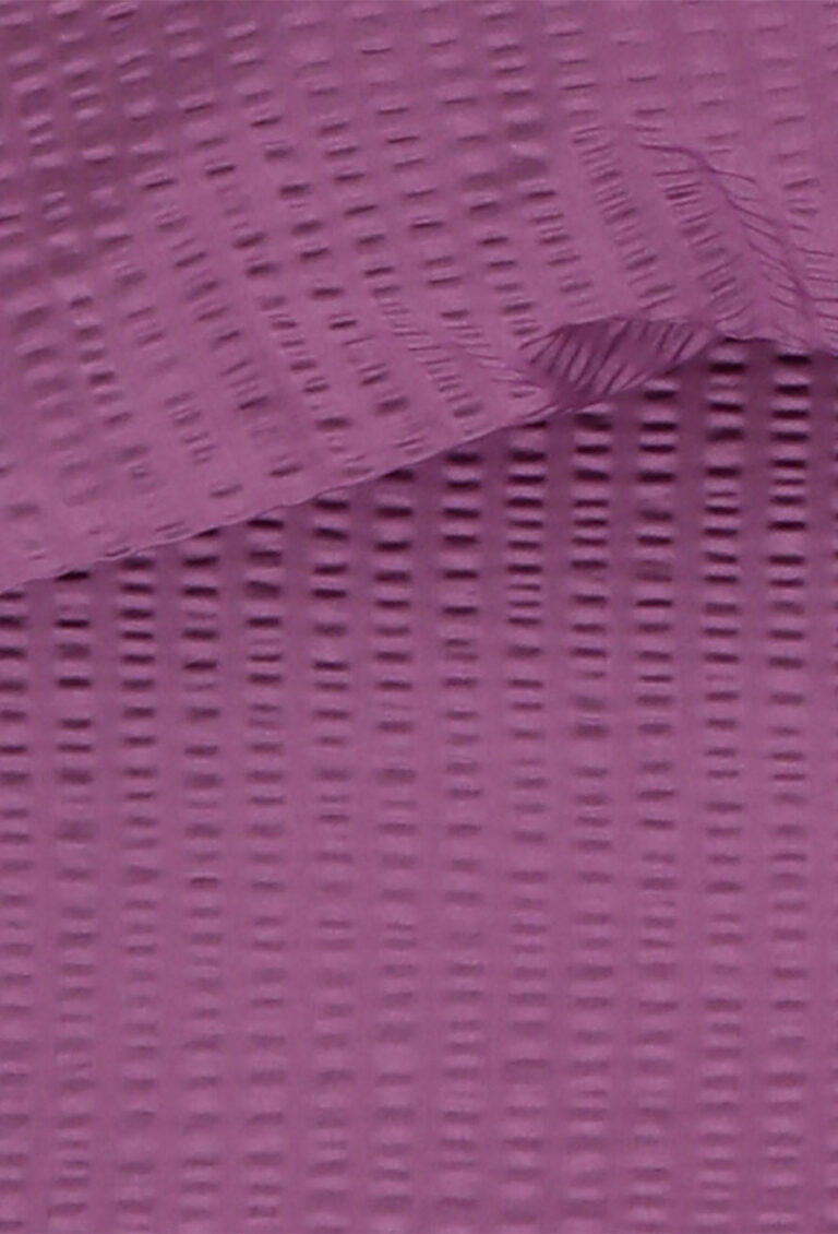 Nahaufnahme einer strukturierten lilafarbenen Oberfläche mit einem gitterartigen Muster und einem gefalteten Abschnitt im oberen Bereich, der Schatten und Tiefe erzeugt.