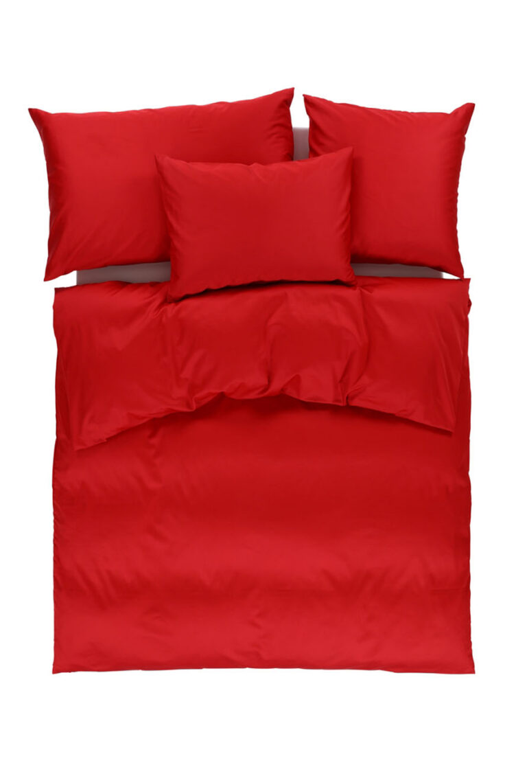 Ein ordentlich gemachtes Bett mit einem leuchtend roten Bettbezug und vier dazu passenden roten Kissen, von oben gesehen vor einem weißen Hintergrund.