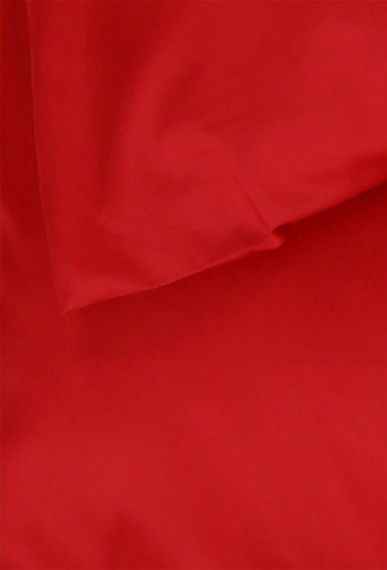 Eine Nahaufnahme eines glatten roten Stoffes, möglicherweise ein Laken oder ein Kleidungsstück, mit sanften Falten und Schatten, die eine weiche Textur erzeugen.