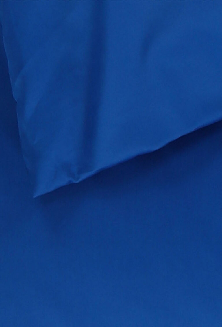 Nahaufnahme eines blauen, teilweise gefalteten Stoffes, der eine glatte Textur und subtile Schatten aufweist.