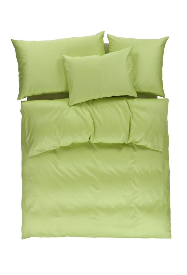 Ein Bett mit grünen Laken und Kissen.