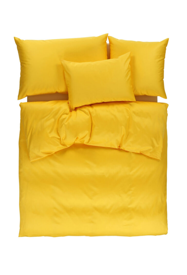 Ein ordentlich gemachtes Bett mit leuchtend gelber Bettwäsche, darunter eine Bettdecke, zwei große Kissen oben und zwei kleinere Kissen, alles von oben gesehen auf weißem Hintergrund.