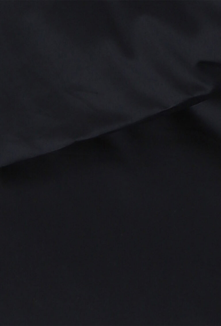 Eine Nahaufnahme eines glatten, dunkelmarineblauen Stoffes mit weichen Falten und subtilen Glanzlichtern, der eine sanfte Textur und ein mattes Finish aufweist.