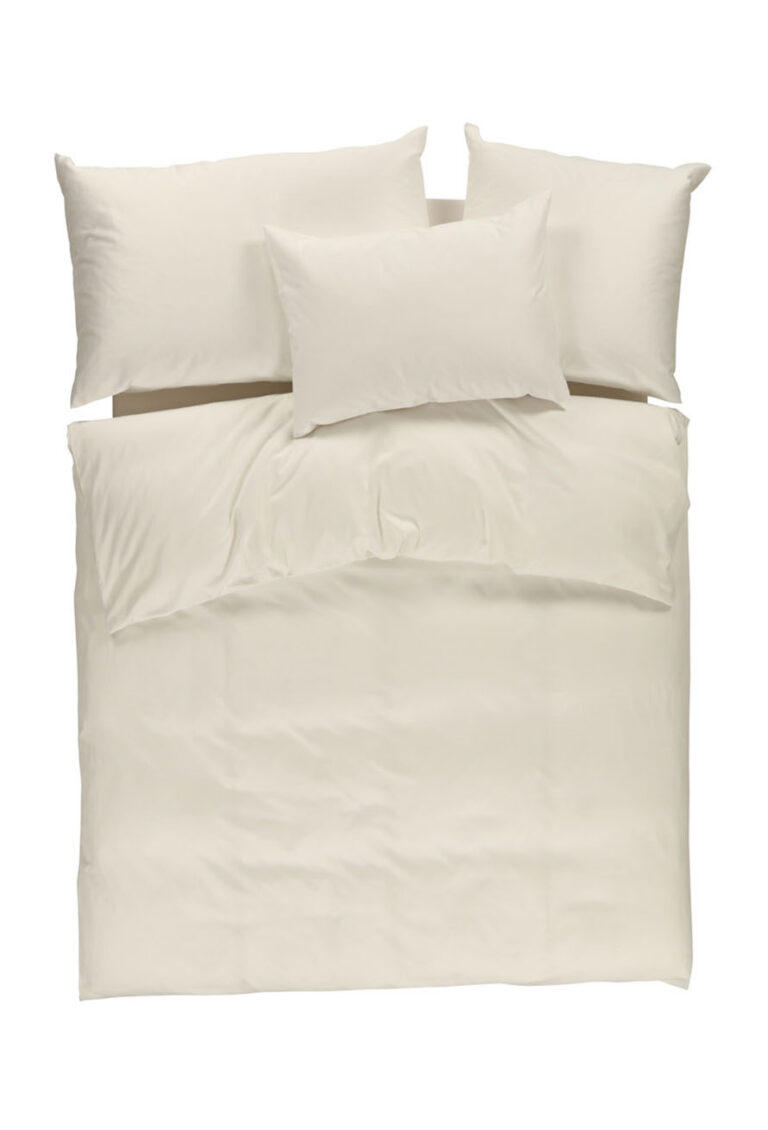 Ein ordentlich gemachtes Bett mit cremefarbenem Bettzeug, einschließlich einer Bettdecke und vier Kissen, von oben gesehen vor einem weißen Hintergrund.